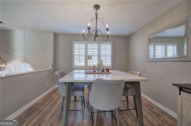 dining area featuring a chandelier, dark hardwood / wood-style floors, and a textured ceiling