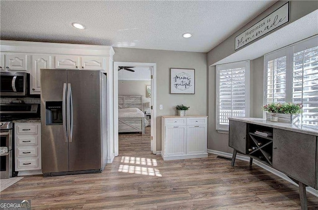 kitchen with white cabinetry, ceiling fan, stainless steel appliances, hardwood / wood-style floors, and a textured ceiling