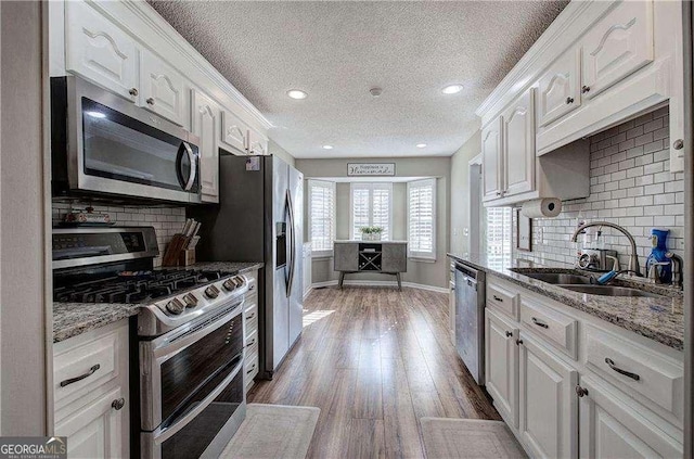 kitchen with white cabinets, backsplash, sink, and appliances with stainless steel finishes