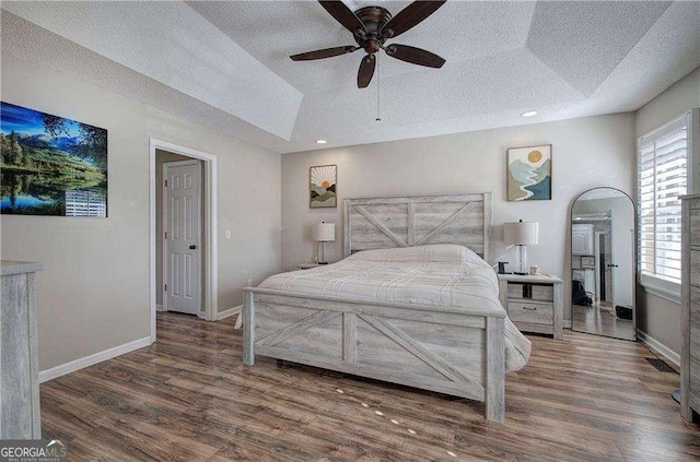 bedroom with a textured ceiling, a raised ceiling, and ceiling fan