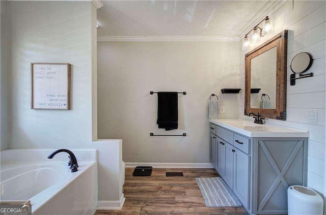 bathroom with a washtub, ornamental molding, a textured ceiling, and hardwood / wood-style flooring