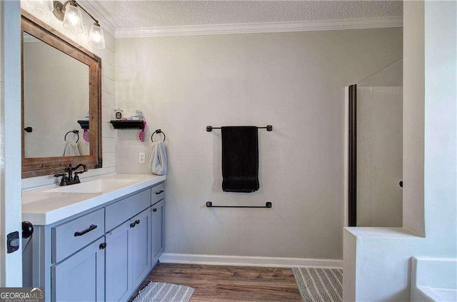 bathroom featuring vanity, wood-type flooring, ornamental molding, and a textured ceiling