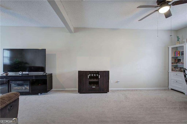 carpeted living room featuring ceiling fan, beamed ceiling, and a textured ceiling