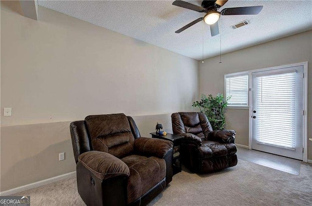 sitting room with a textured ceiling, light colored carpet, and ceiling fan