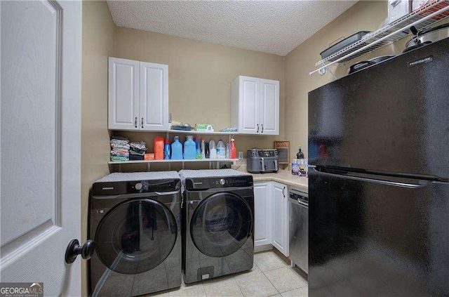 laundry room with washing machine and dryer, light tile patterned floors, and a textured ceiling