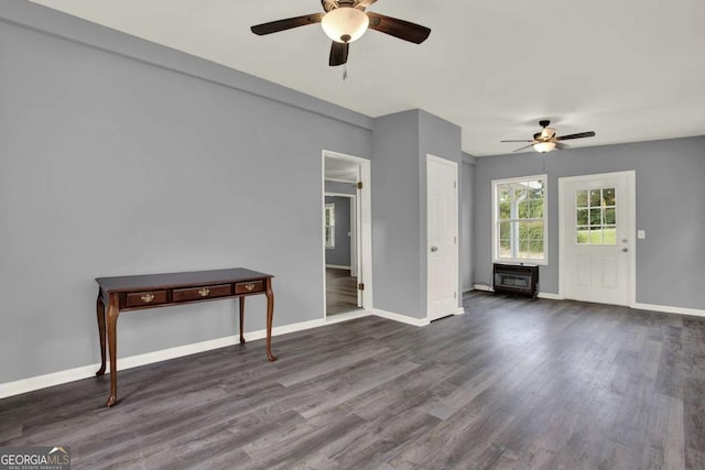 unfurnished living room with heating unit, ceiling fan, and dark wood-type flooring