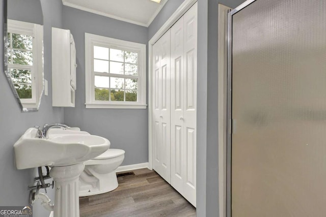 bathroom with toilet, a shower with door, wood-type flooring, and ornamental molding