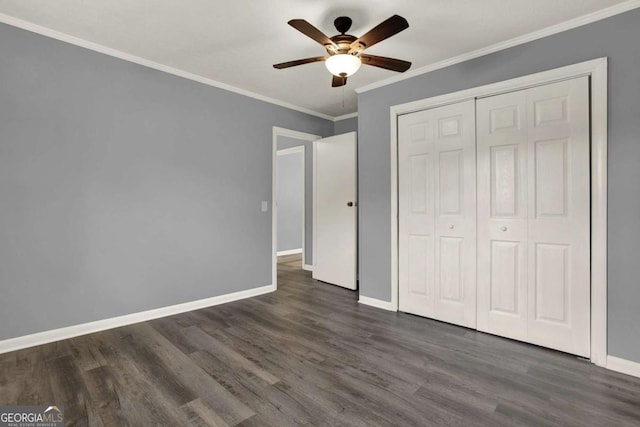 unfurnished bedroom featuring dark wood-type flooring, a closet, ceiling fan, and crown molding