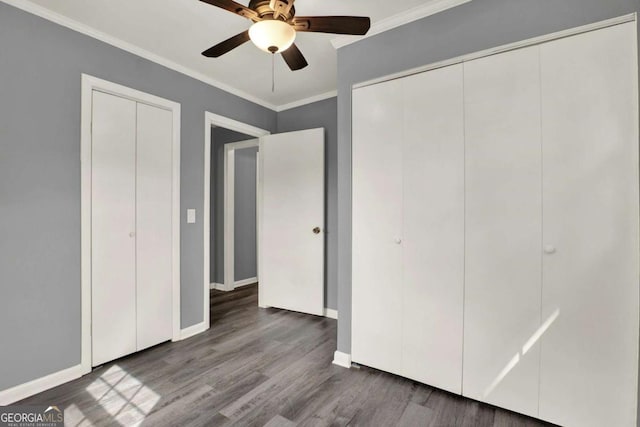 unfurnished bedroom with hardwood / wood-style floors, ceiling fan, crown molding, and two closets