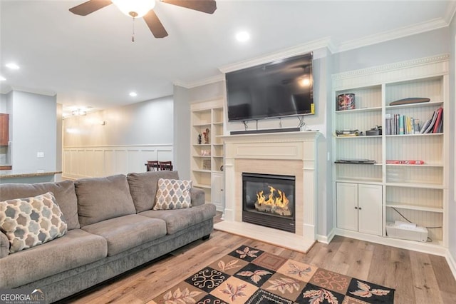 living room featuring light hardwood / wood-style floors, ceiling fan, and crown molding