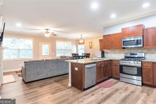 kitchen featuring ceiling fan, hanging light fixtures, light hardwood / wood-style flooring, appliances with stainless steel finishes, and ornamental molding