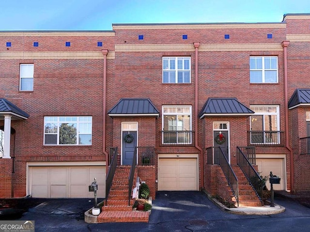 multi unit property with a garage, a standing seam roof, metal roof, and brick siding