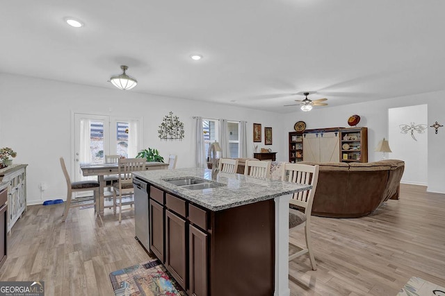 kitchen with sink, light stone counters, light hardwood / wood-style floors, stainless steel dishwasher, and dark brown cabinetry