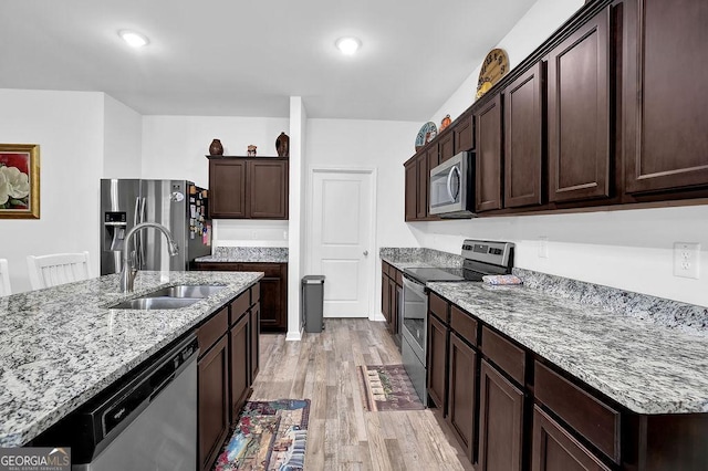 kitchen with sink, dark brown cabinetry, light hardwood / wood-style flooring, and appliances with stainless steel finishes