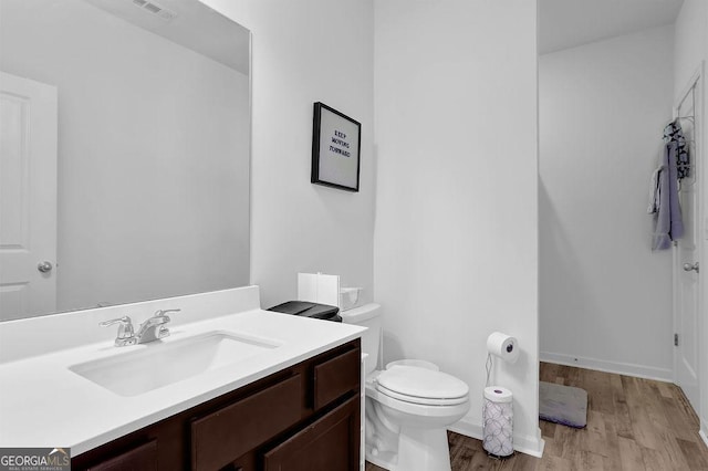 bathroom with toilet, vanity, and hardwood / wood-style flooring