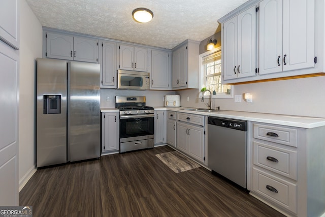 kitchen with sink, a textured ceiling, appliances with stainless steel finishes, and dark wood-type flooring