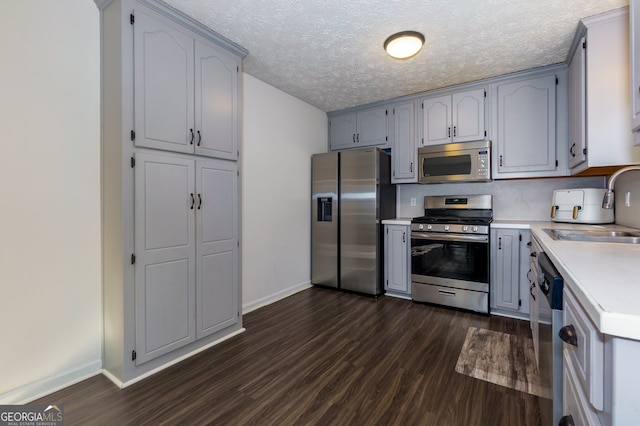 kitchen featuring dark hardwood / wood-style flooring, sink, stainless steel appliances, and a textured ceiling