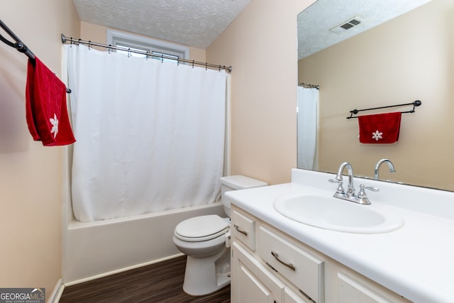 full bathroom with vanity, hardwood / wood-style flooring, toilet, shower / bath combo with shower curtain, and a textured ceiling