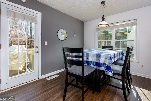 dining room with a textured ceiling, plenty of natural light, and dark hardwood / wood-style floors