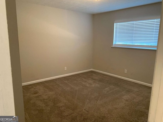 spare room featuring dark carpet