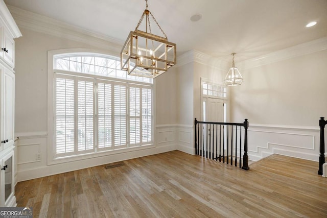 unfurnished room featuring a healthy amount of sunlight, light wood-type flooring, and a notable chandelier