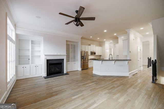 unfurnished living room with ceiling fan, light hardwood / wood-style floors, sink, and crown molding