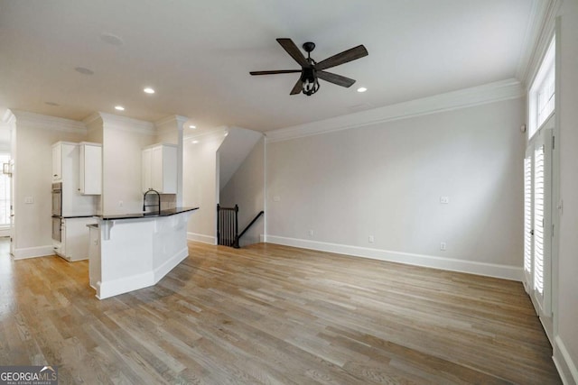 kitchen with ceiling fan, wall oven, light wood-type flooring, white cabinets, and ornamental molding