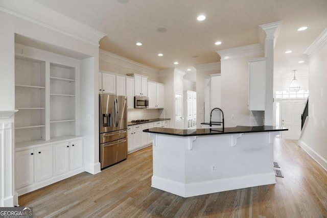 kitchen featuring a breakfast bar area, kitchen peninsula, white cabinets, and stainless steel appliances