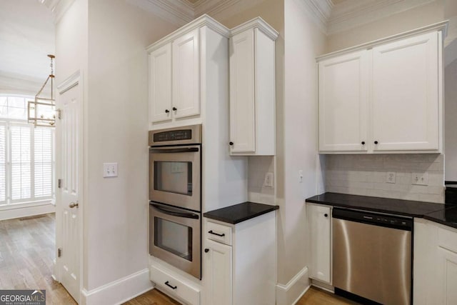 kitchen with decorative backsplash, stainless steel appliances, crown molding, a chandelier, and white cabinetry