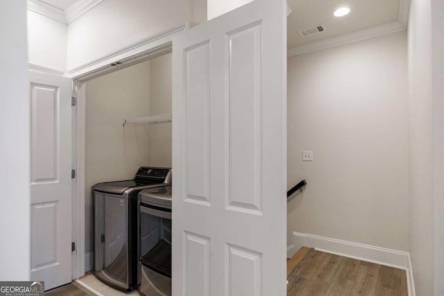 washroom with separate washer and dryer, crown molding, and light hardwood / wood-style floors