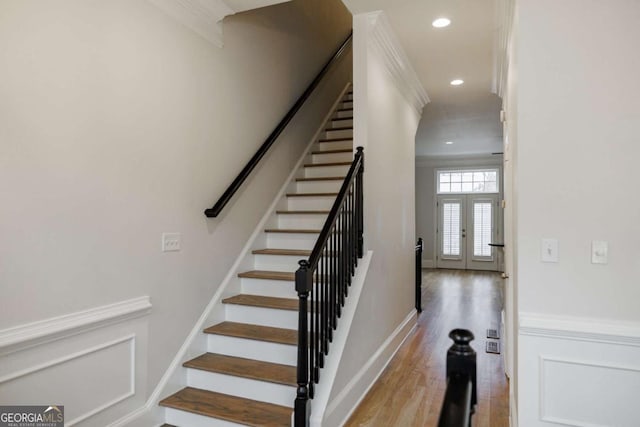 staircase with hardwood / wood-style floors, crown molding, and french doors