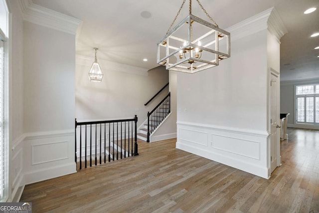 spare room featuring a chandelier, wood-type flooring, and ornamental molding