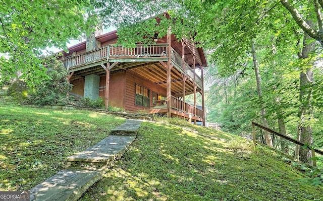 back of property with a wooden deck and a lawn