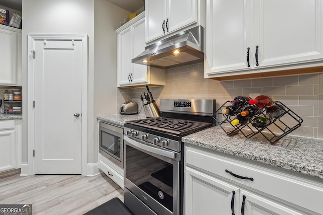 kitchen featuring appliances with stainless steel finishes, tasteful backsplash, light stone counters, light hardwood / wood-style flooring, and white cabinets