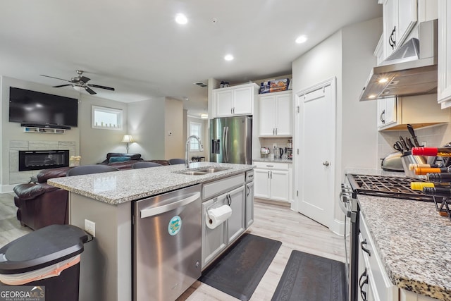 kitchen featuring tasteful backsplash, stainless steel appliances, sink, white cabinets, and an island with sink