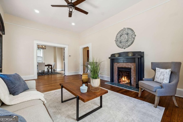 living room featuring hardwood / wood-style floors, a brick fireplace, and ceiling fan