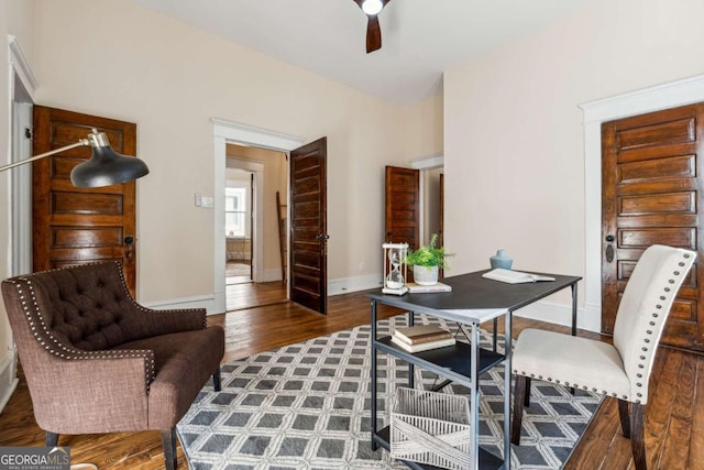 home office with ceiling fan and dark hardwood / wood-style flooring