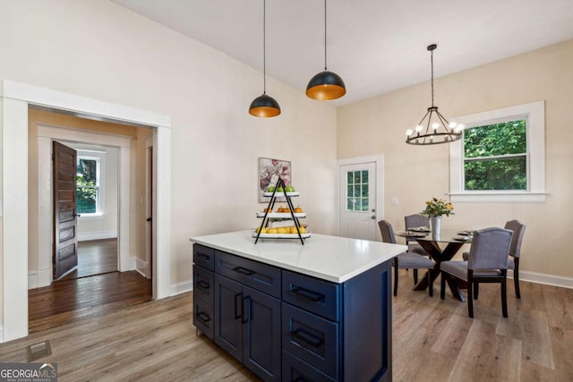 kitchen with blue cabinetry, a kitchen island, light hardwood / wood-style floors, and decorative light fixtures