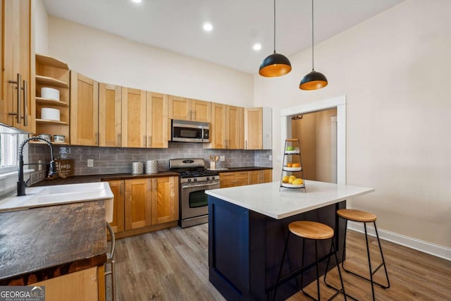 kitchen with decorative backsplash, stainless steel appliances, sink, decorative light fixtures, and a center island