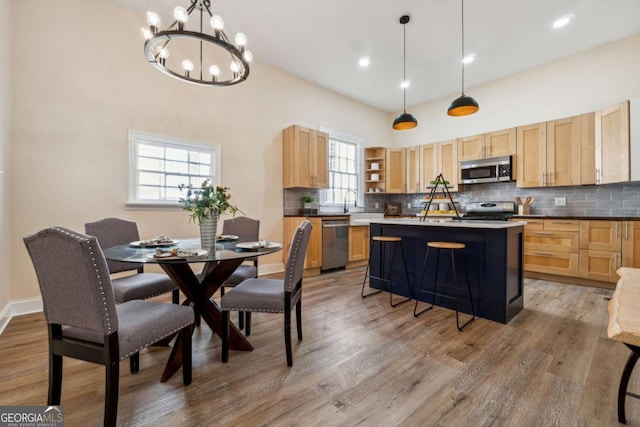 kitchen with decorative light fixtures, a center island, a breakfast bar area, and appliances with stainless steel finishes