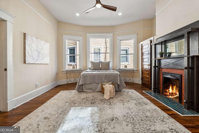 bedroom featuring ceiling fan, dark hardwood / wood-style flooring, and a tiled fireplace