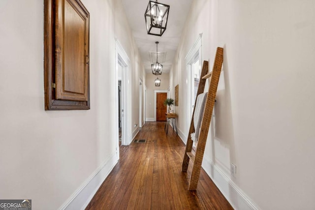 hall with a notable chandelier and dark hardwood / wood-style floors