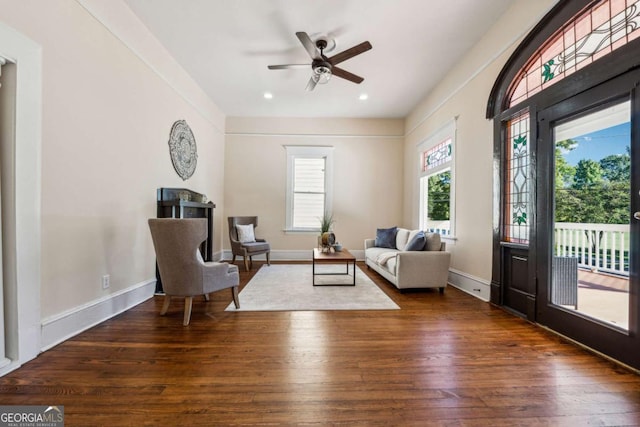 living area with ceiling fan and dark wood-type flooring