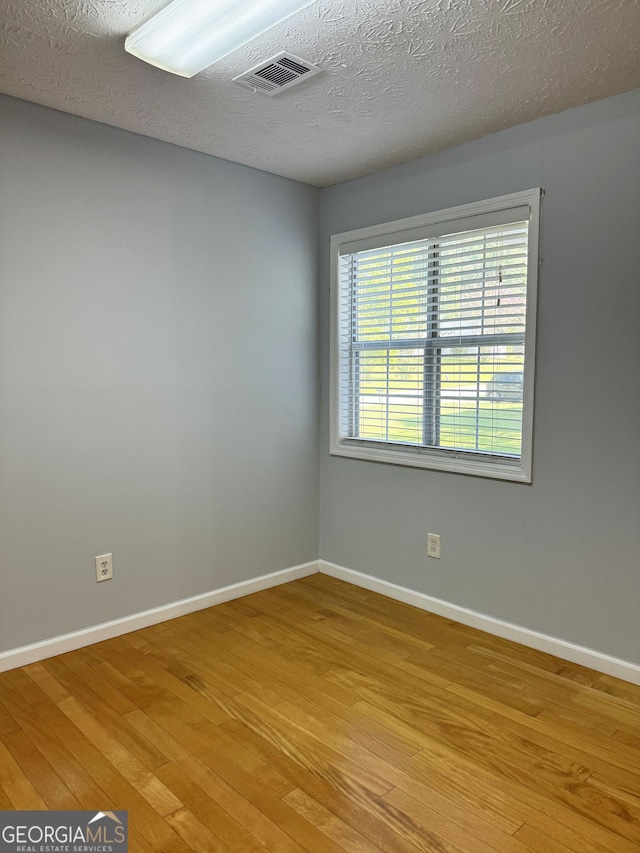 empty room with a textured ceiling and light wood-type flooring