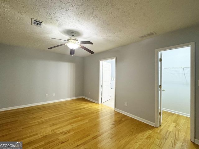 spare room featuring ceiling fan, light hardwood / wood-style floors, and a textured ceiling