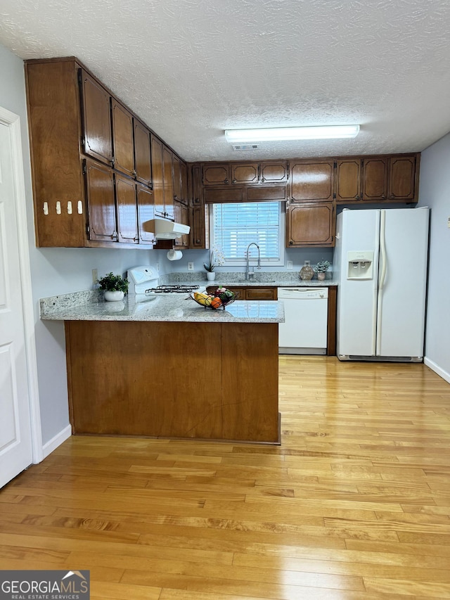 kitchen with kitchen peninsula, sink, white appliances, and a textured ceiling