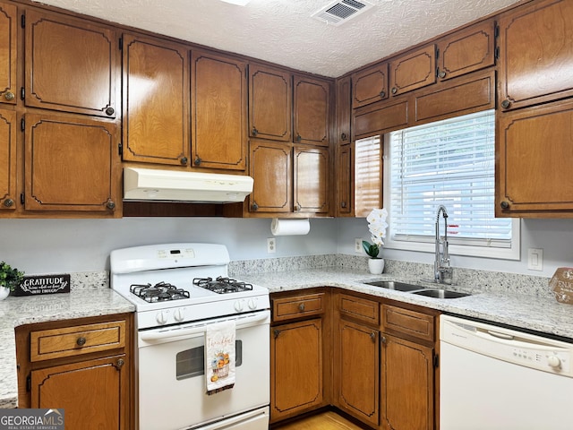 kitchen featuring a textured ceiling, white appliances, and sink