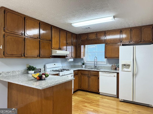 kitchen featuring a textured ceiling, kitchen peninsula, white appliances, and sink