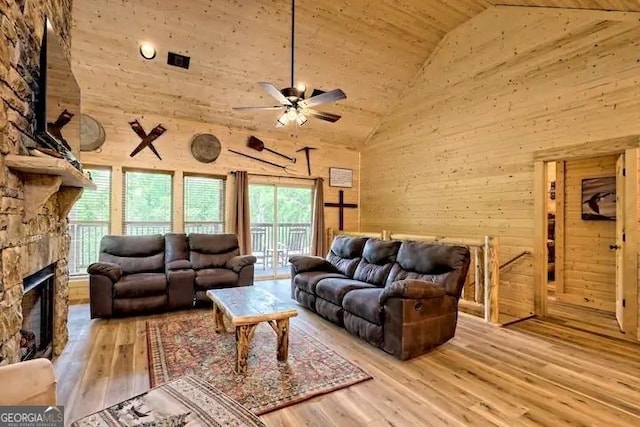 living room with high vaulted ceiling, light hardwood / wood-style floors, ceiling fan, and a stone fireplace