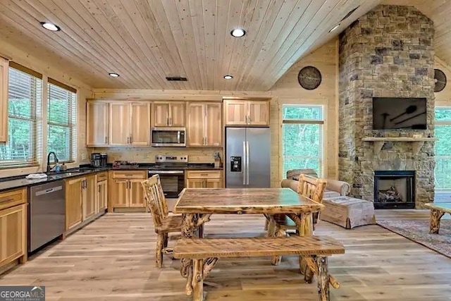 kitchen featuring a stone fireplace, wooden ceiling, appliances with stainless steel finishes, light hardwood / wood-style flooring, and sink